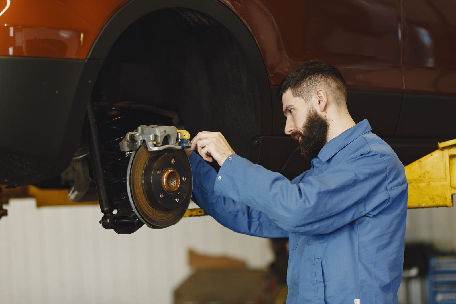 Technician fitting a brake disc on a vehicle raised on a lift