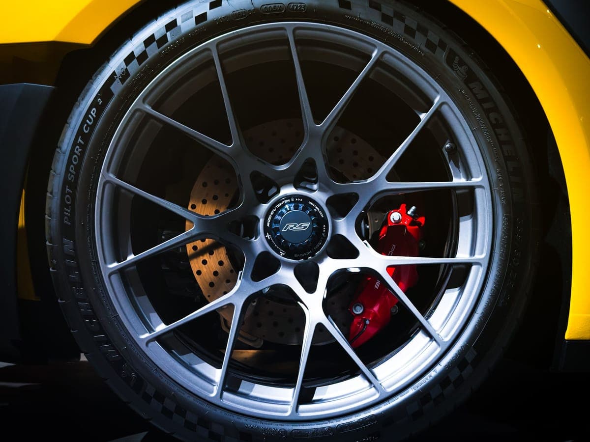 Centre-lock alloy wheel and red brake caliper on a yellow Porsche sports car