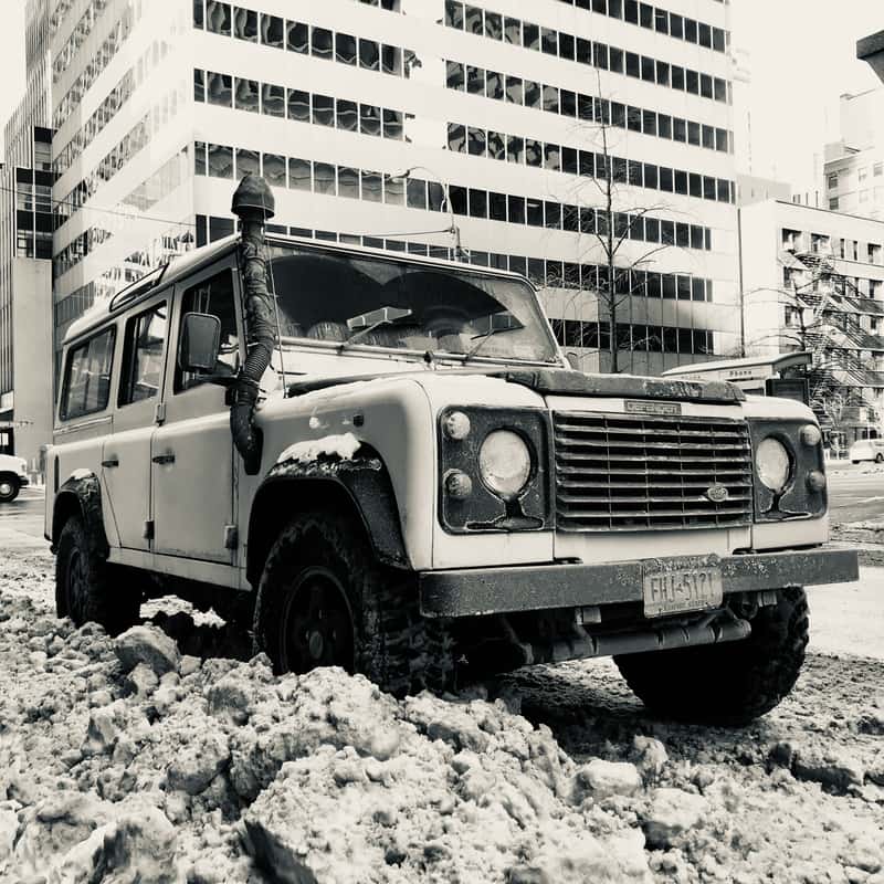 Land Rover Defender 110 parked in snow on a city street